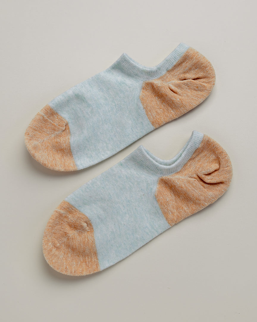Pair of light blue and brown ankle socks on a beige background
