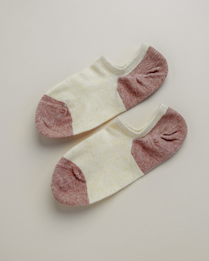 Pair of white socks with pink toes and heels on a beige background