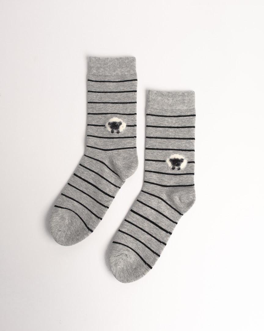 A pair of gray crew socks with thin black horizontal stripes and a small black-and-white sheep motif near the cuff, displayed on a clean white background.