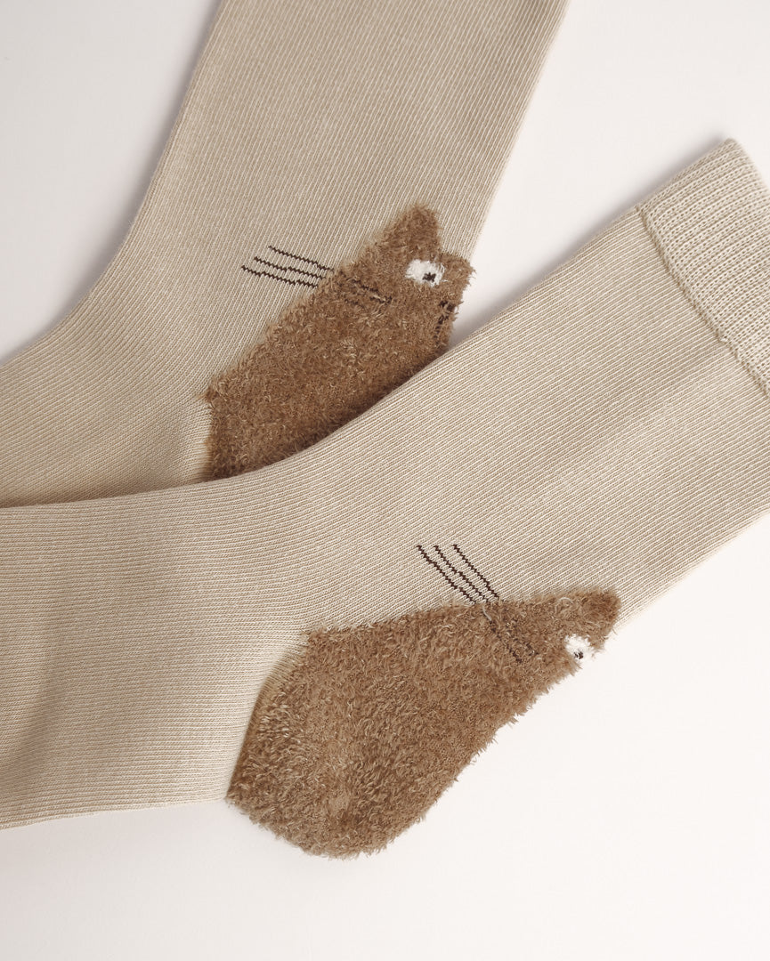 A pair of beige ribbed socks with brown fuzzy cat-shaped heels, shown on a plain light background.
