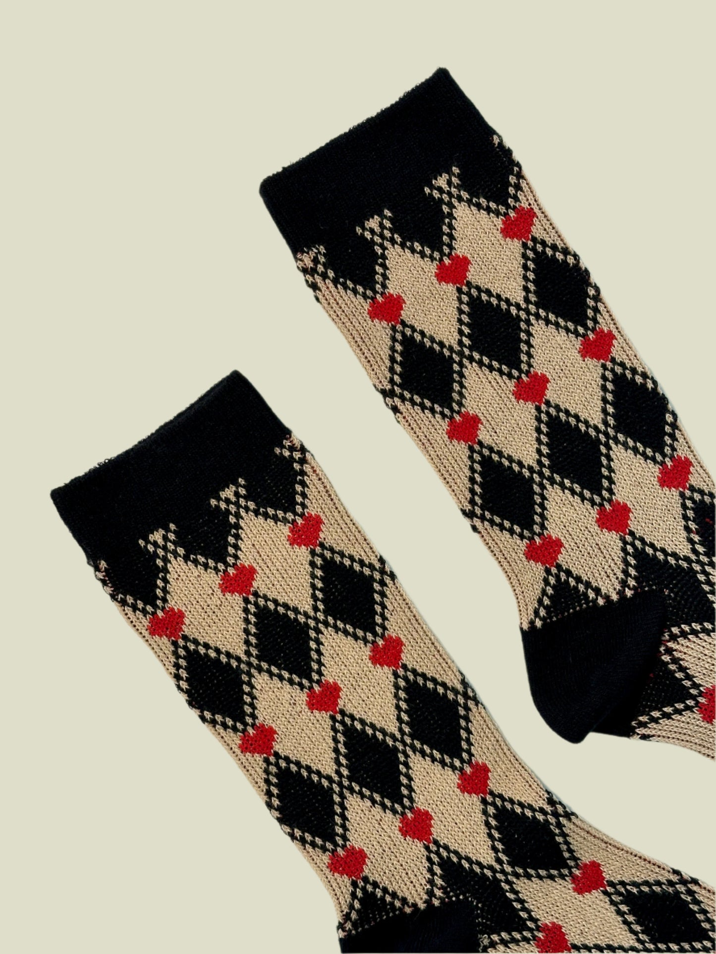 Pair of socks with argyle pattern and red hearts on a light gray background