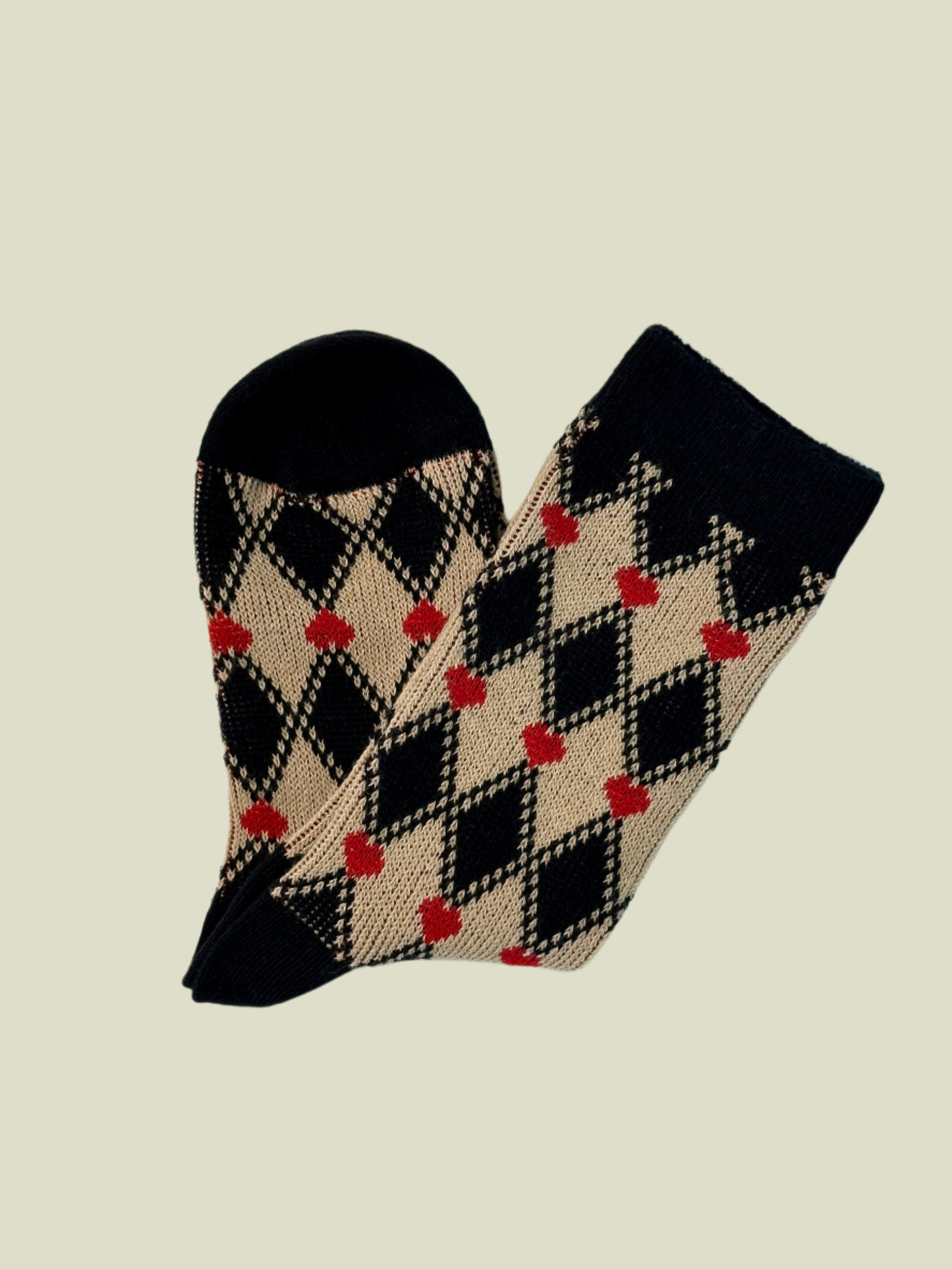 Pair of socks with black, beige, and red argyle pattern on a light gray background