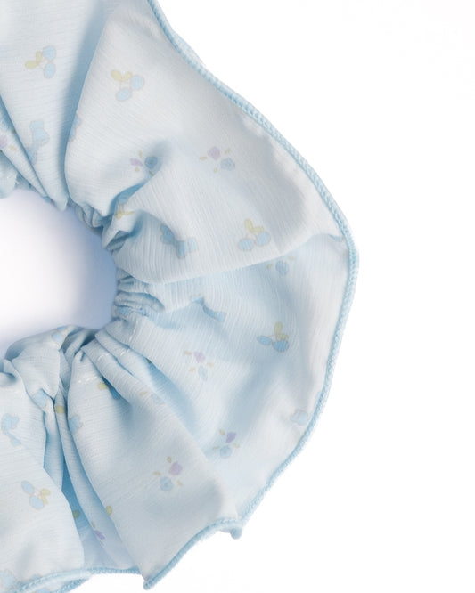 Close-up of light blue sheer floral hair scrunchie showing fabric texture and blue print details