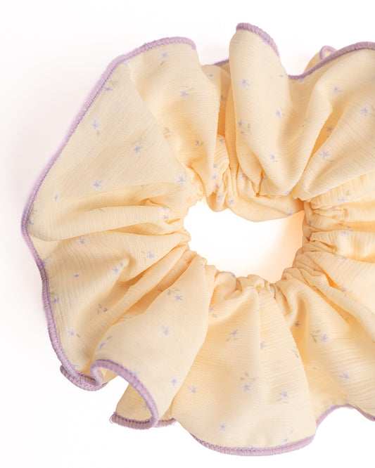 Close-up of yellow sheer floral hair scrunchie showing fabric texture and lavender trim details