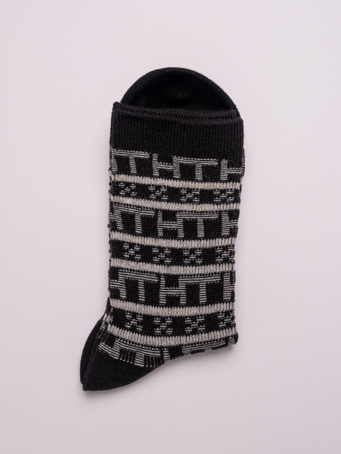 Black sock with white pattern on a light gray background