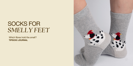  Person wearing grey crew socks with spotted dog motifs beside the title “Socks for Smelly Feet: Which Fibres Hold the Smell?”