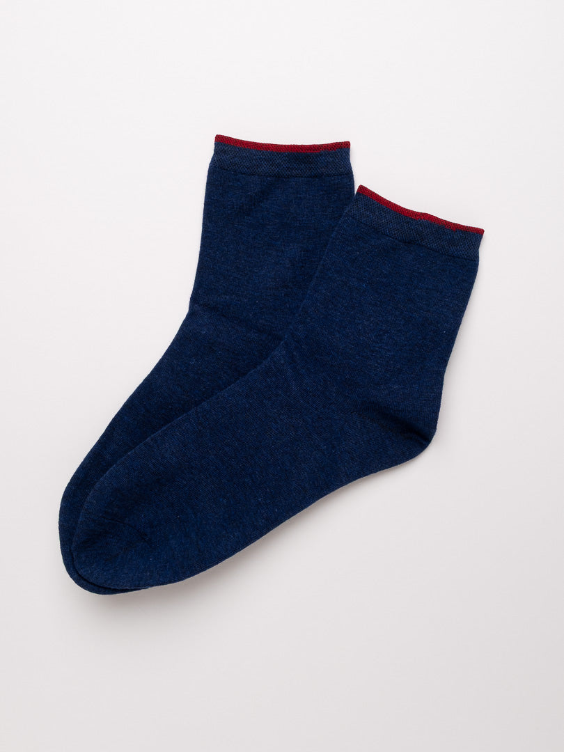 Pair of navy blue socks with red trim on a light gray background