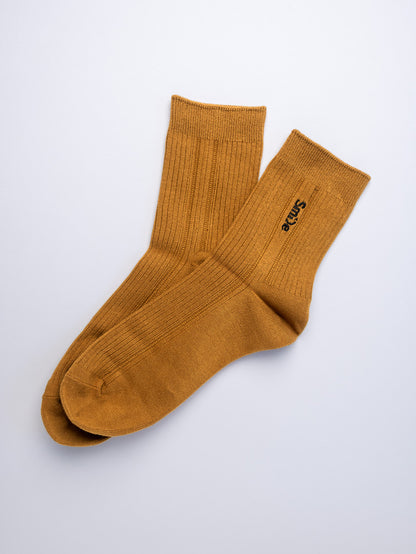 Pair of mustard yellow socks on a light gray background