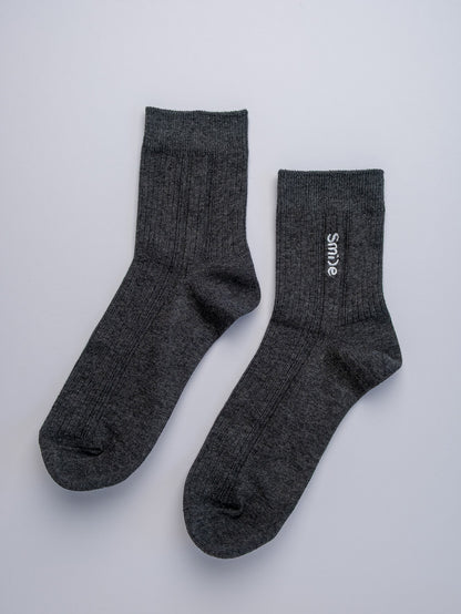 Pair of gray socks with a brand logo on a light gray background