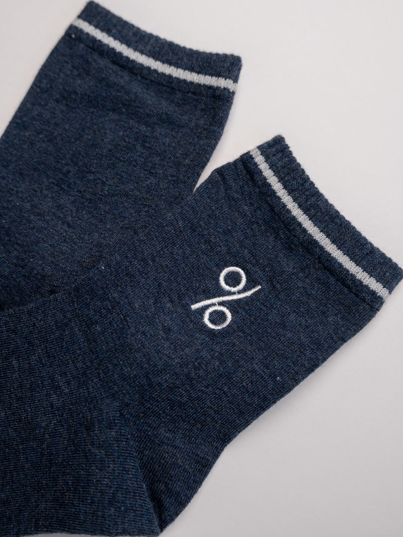 Pair of dark blue socks with a white logo on a light gray background
