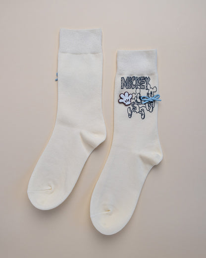 Two white socks with cartoon character design on a beige background