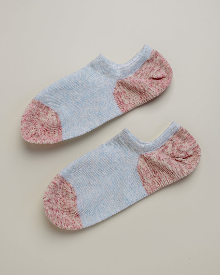 Pair of light blue and pink ankle socks on a beige background
