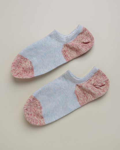 Pair of light blue and pink ankle socks on a beige background