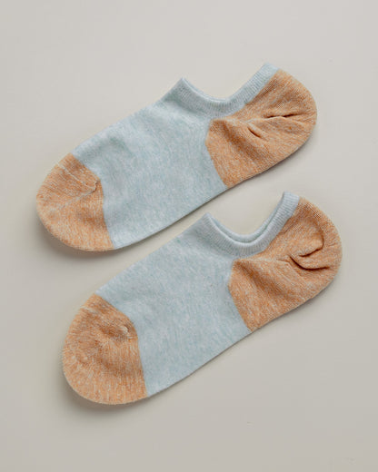Pair of light blue and brown ankle socks on a beige background