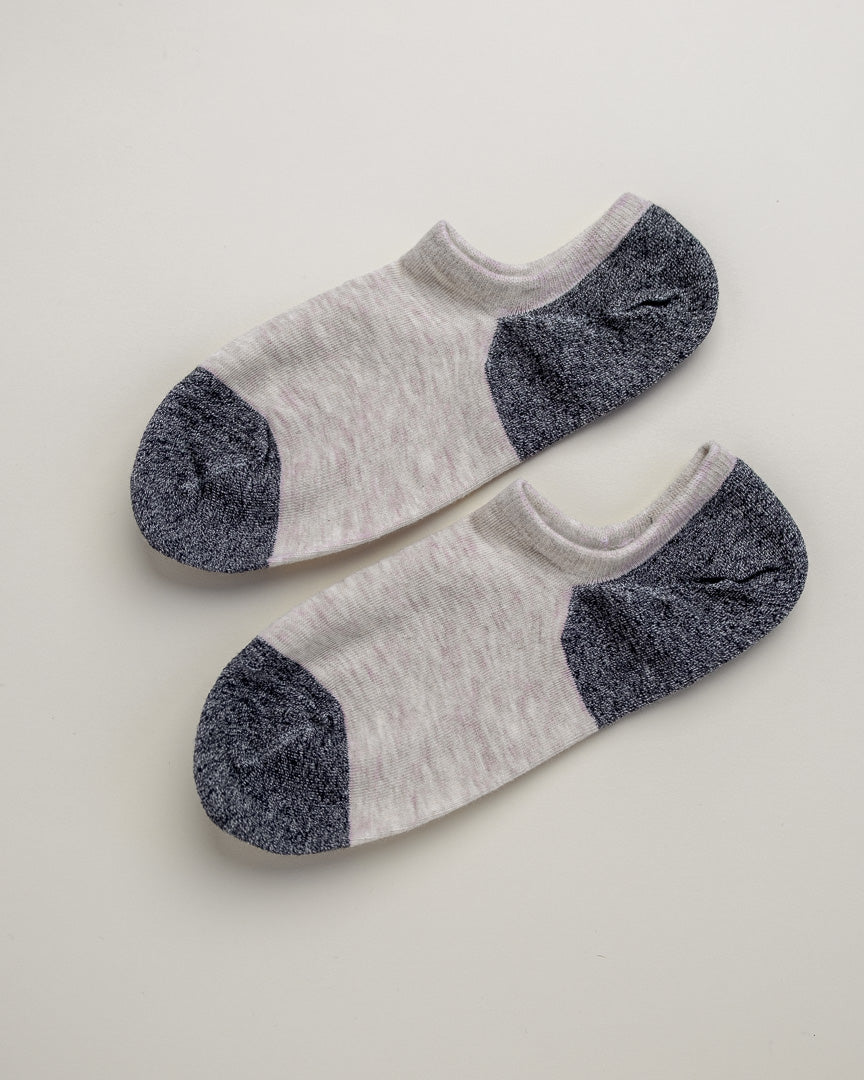 Pair of white socks with gray toes and heels on a light beige background