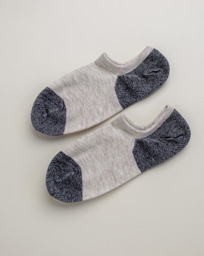 Pair of white socks with gray toes and heels on a light beige background