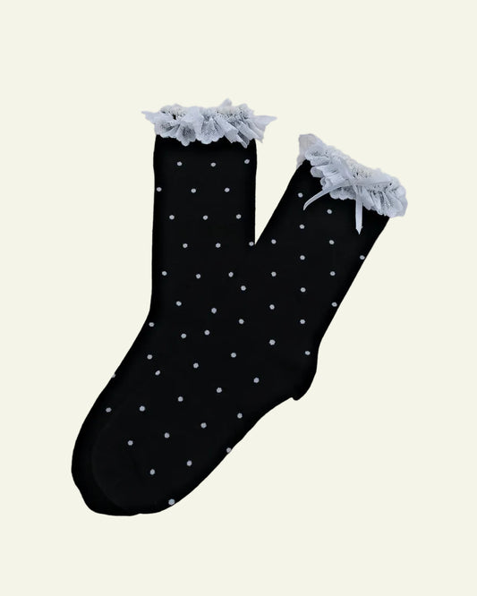 Black socks with white polka dots and lace trim on a beige background