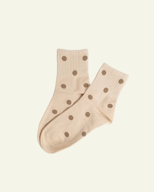 Pair of beige socks with brown polka dots on a light gray background