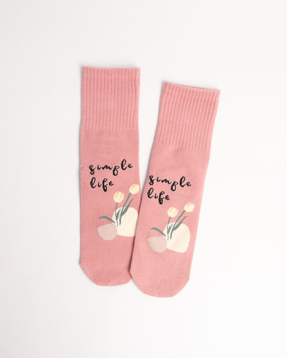 Pink socks with 'simple life' text and floral design on a white background