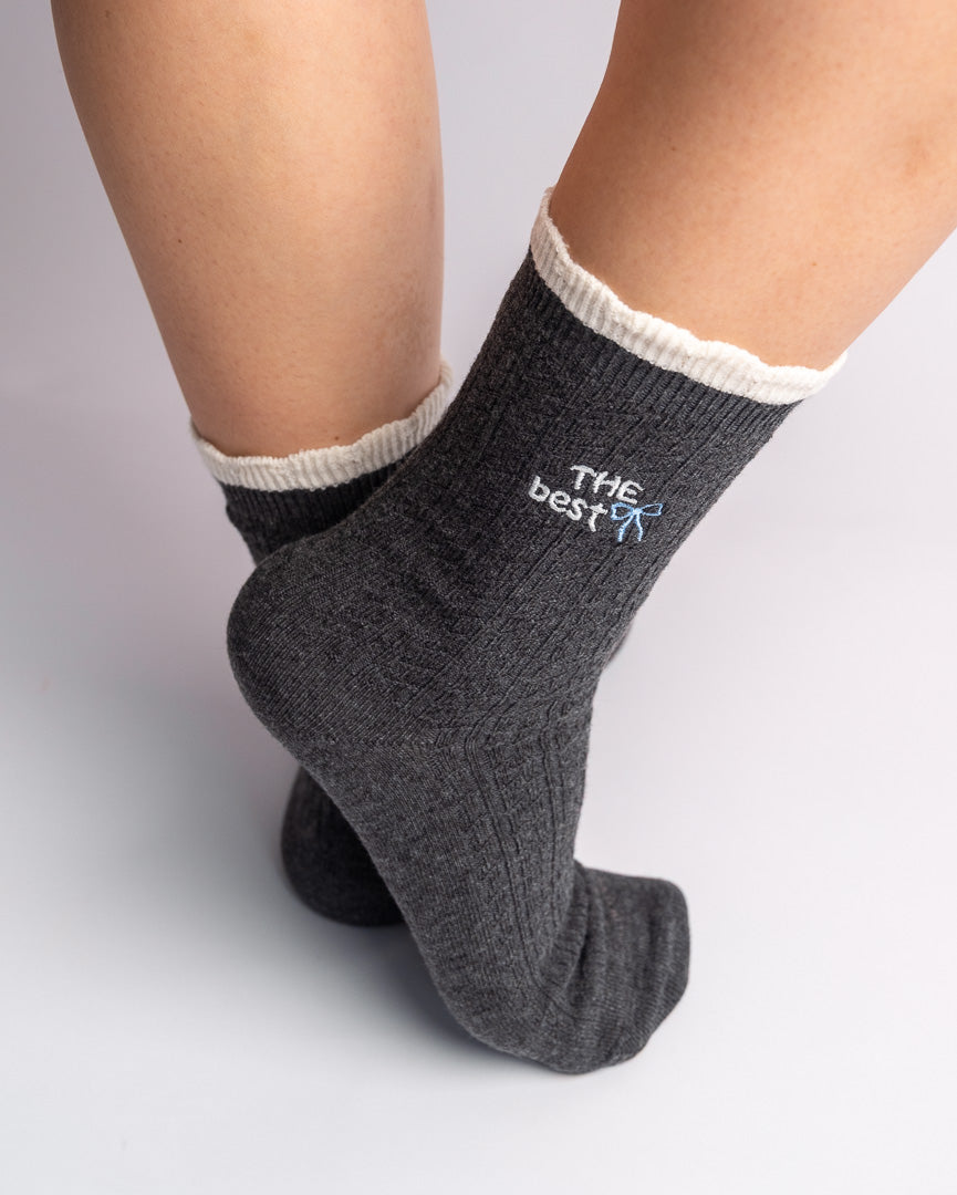 Woman wearing grey ribbed cotton crew socks with contrast ruffle cuff and bow embroidery