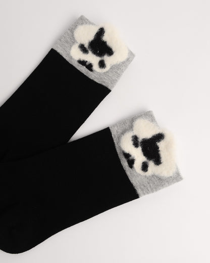 Black crew socks with gray cuffs featuring a fluffy white and black paw print design, displayed on a light gray background.