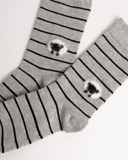 A pair of gray knit socks with thin black horizontal stripes and a small fluffy black-and-white sheep motif near the lower calf, displayed on a clean white background.