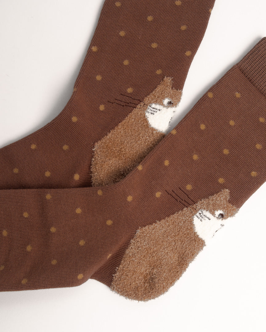 A pair of brown crew socks with small tan polka dots and a plush brown hedgehog design on the toe, shown on a white background.