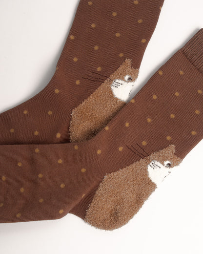 A pair of brown crew socks with small tan polka dots and a plush brown hedgehog design on the toe, shown on a white background.
