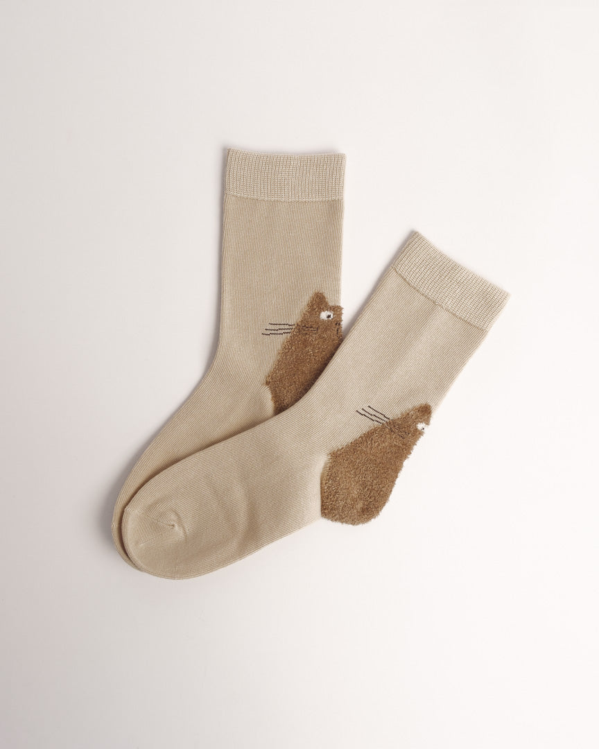 A pair of beige crew socks with brown cat-shaped heel and toe protectors, displayed on a clean off-white background.