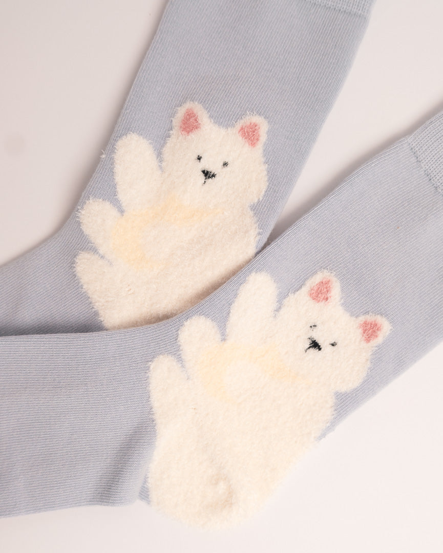 A pair of light blue ribbed socks featuring large, fluffy cream-colored bear appliques on the front, with pink inner ears and small black stitched facial details.