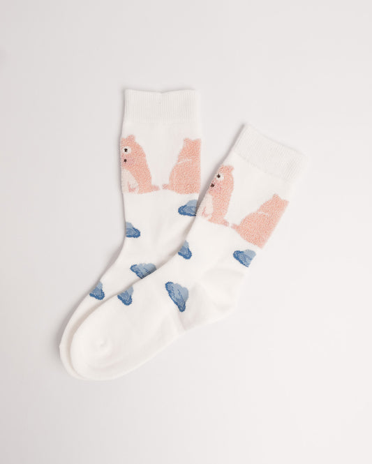 A pair of white crew socks featuring a pattern of pink seals and blue rocks, displayed on a clean white background.