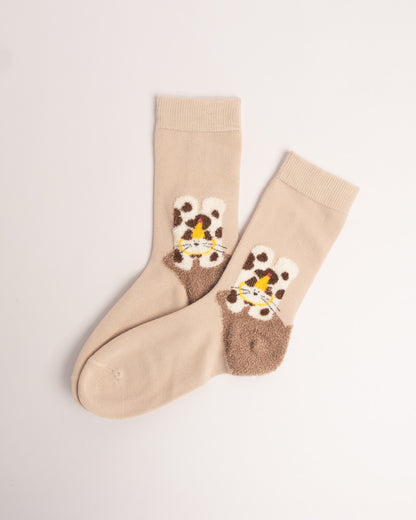 Beige cotton crew socks featuring a fuzzy spotted cat wearing a party hat