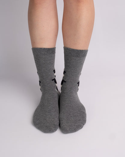 A pair of heather gray crew socks with black side patterns, worn on a person's legs against a light gray studio background.