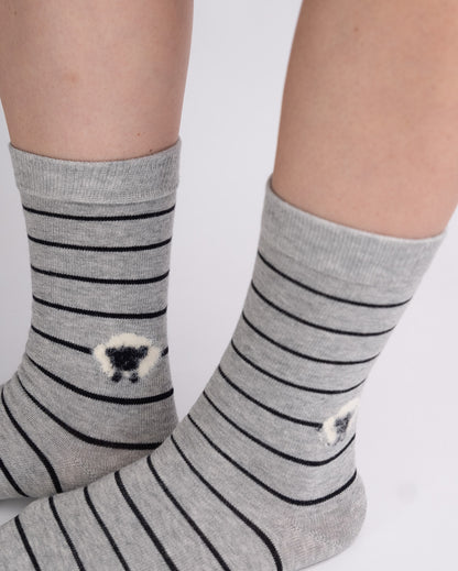 Gray crew socks with thin black horizontal stripes and small white sheep motifs near the cuffs, worn on feet against a plain light background.