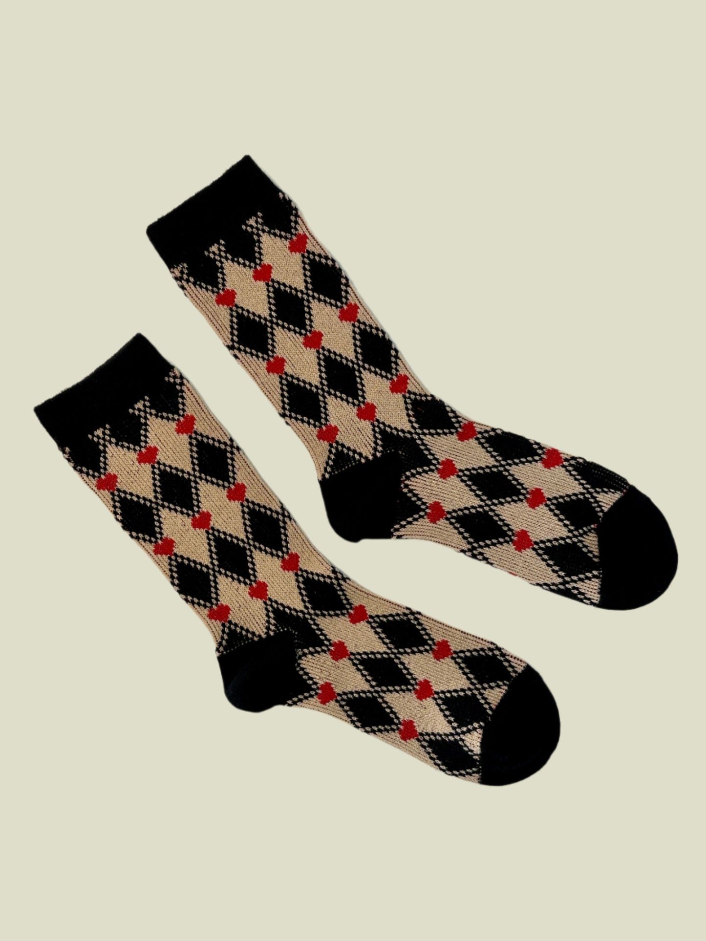 Pair of black, beige, and red checkered socks on a white background