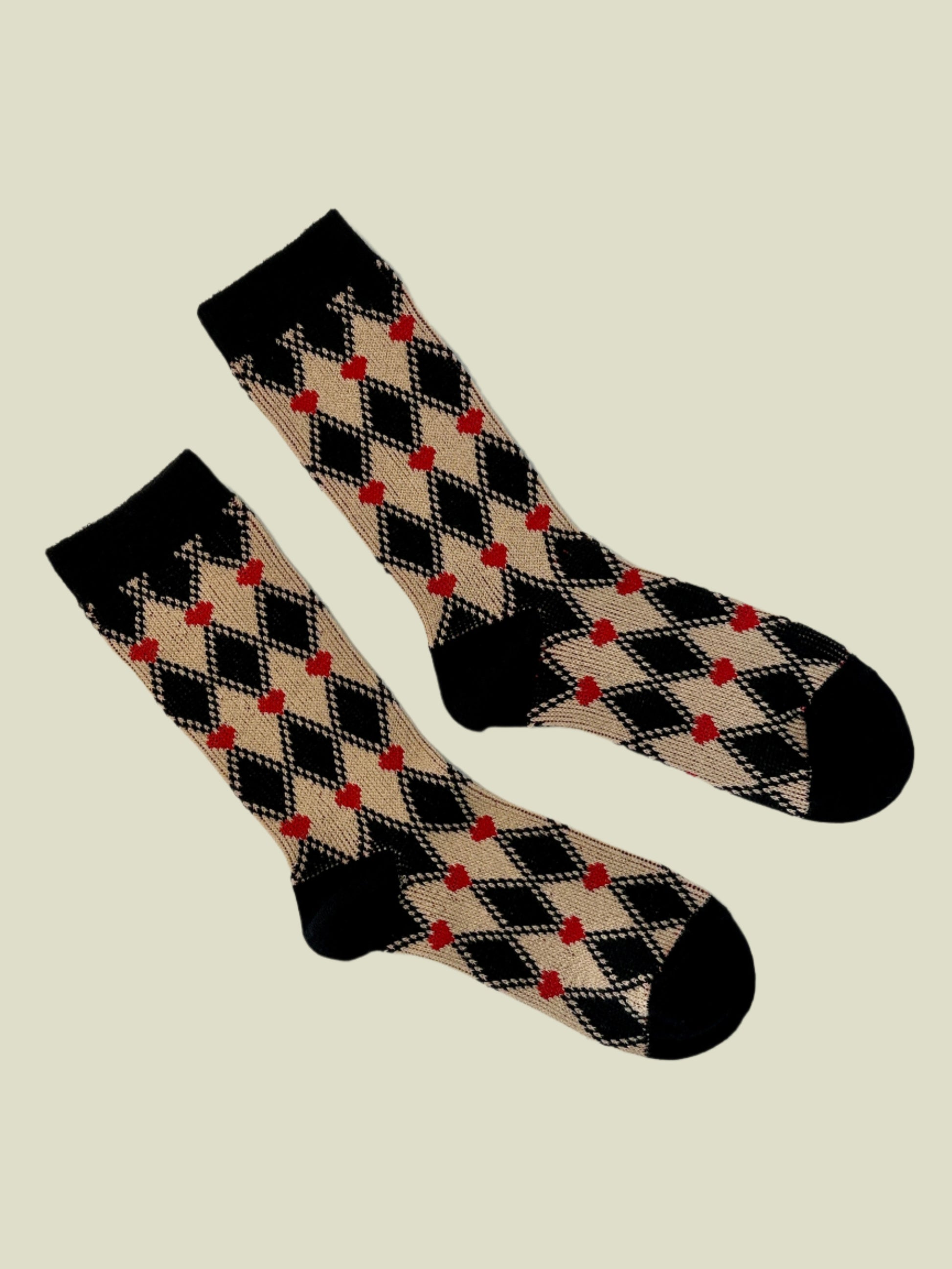 Pair of black, beige, and red checkered socks on a white background