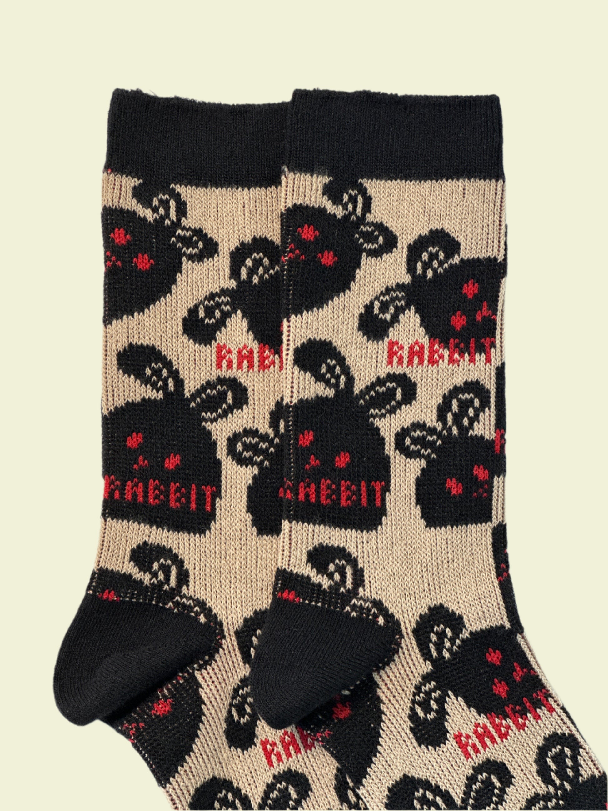 Beige socks with black rabbit pattern and red text on a white background