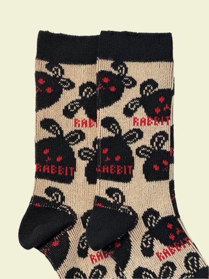 Beige socks with black rabbit pattern and red text on a white background