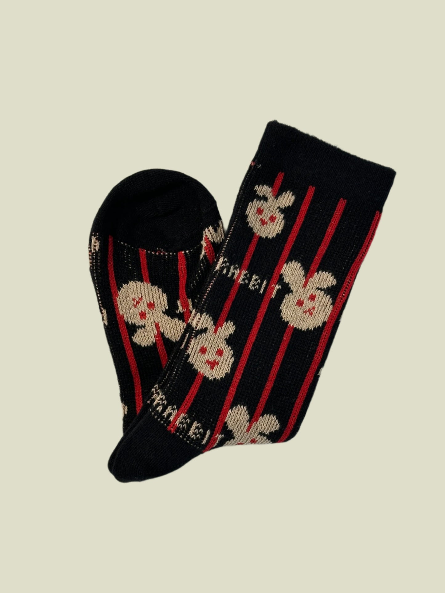 Black sock with red stripes and white floral patterns on a light gray background