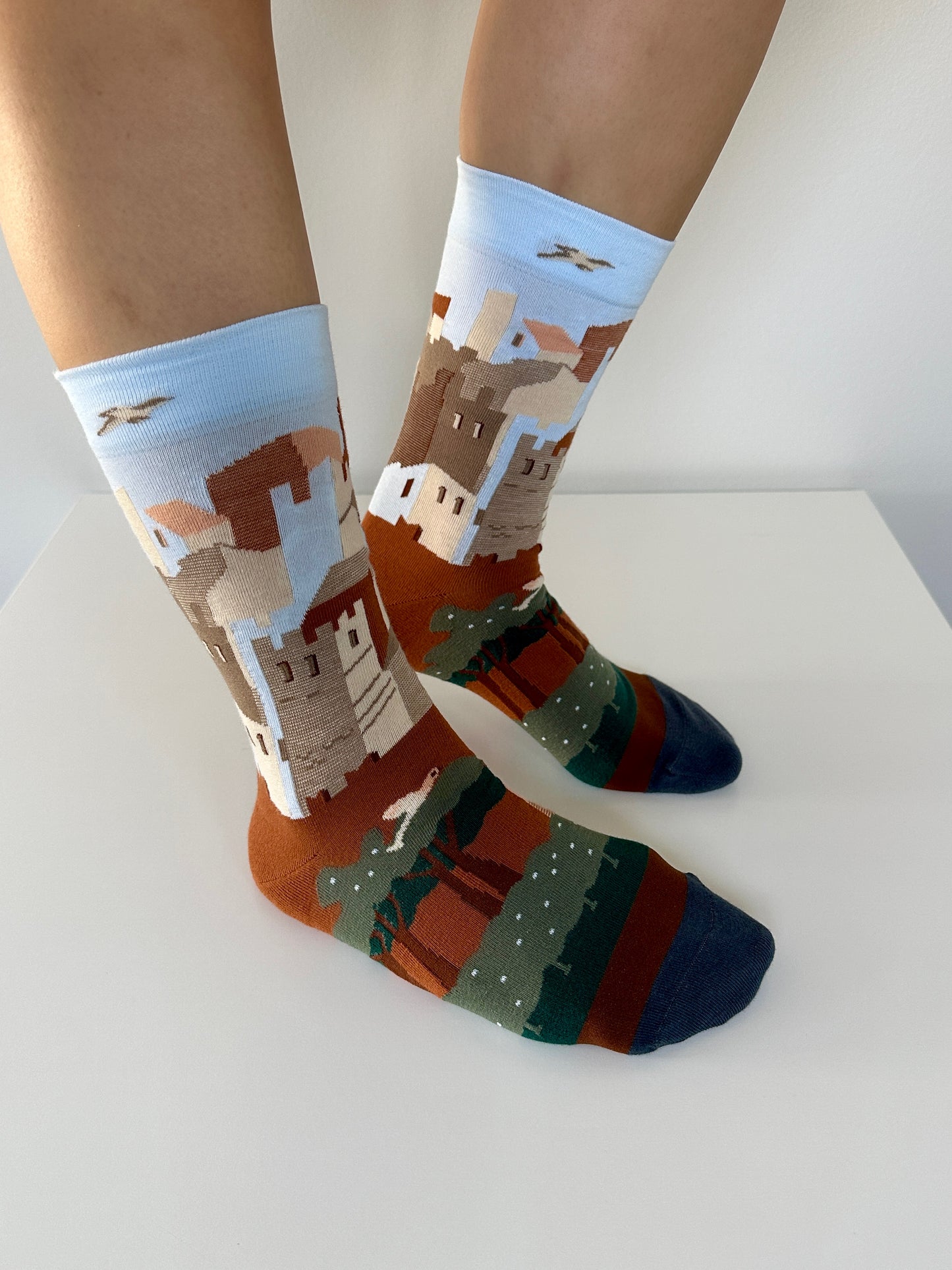 Colorful socks with castle design worn by a person on a white surface