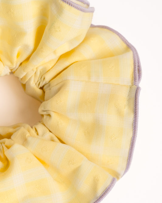 Close-up of yellow gingham cotton scrunchie showing fabric texture and purple edge trim details