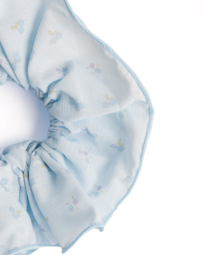 Close-up of light blue sheer floral hair scrunchie showing fabric texture and blue print details