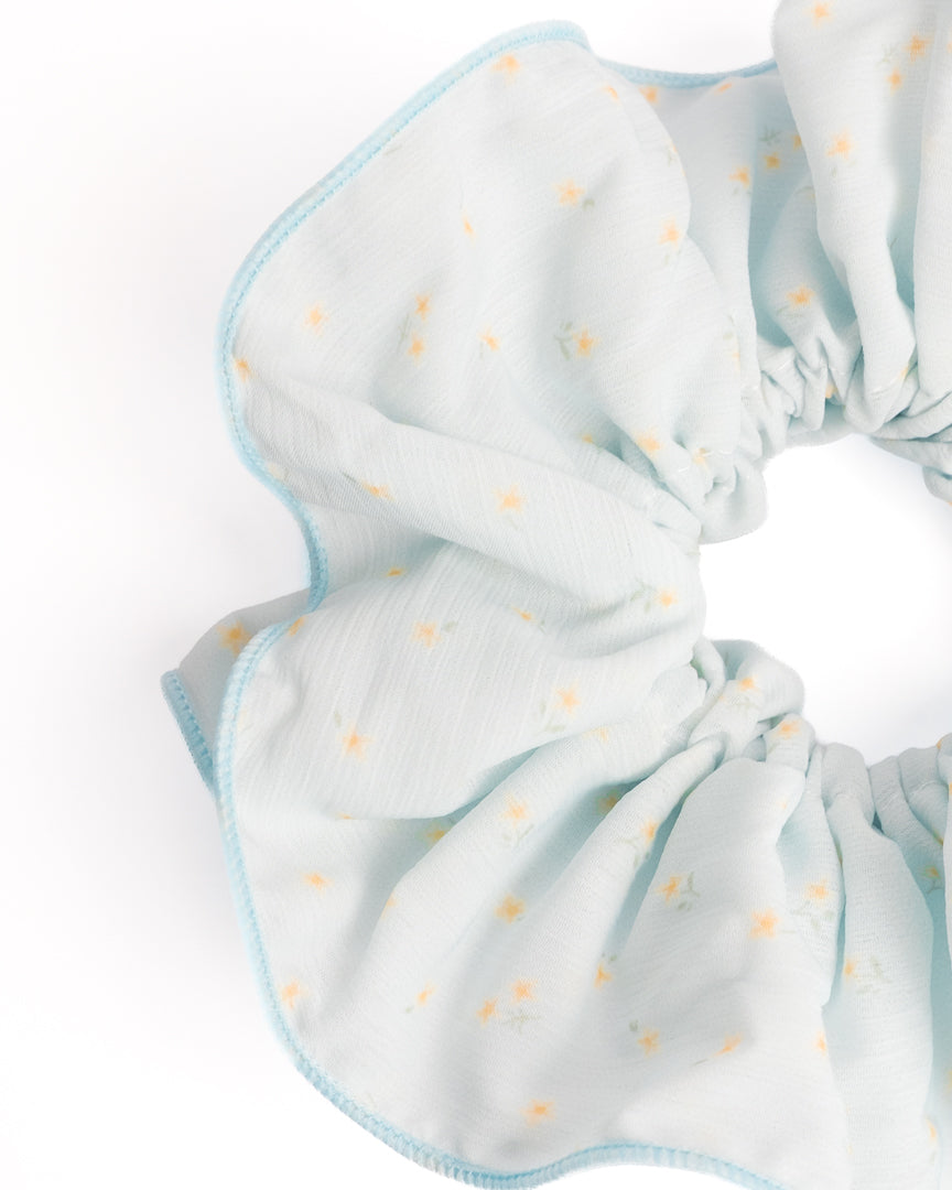 Side view of oversized fluffy light blue sheer XL scrunchie with daisy print highlighting voluminous ruffles
