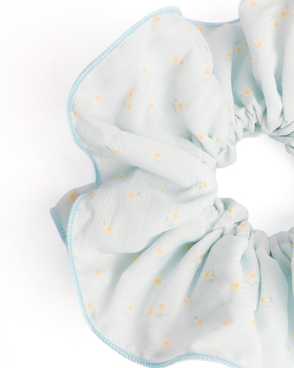 Side view of oversized fluffy light blue sheer XL scrunchie with daisy print highlighting voluminous ruffles