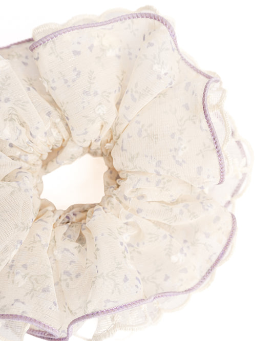 Close-up of cream sheer floral hair scrunchie showing fabric texture and scalloped lace trim details