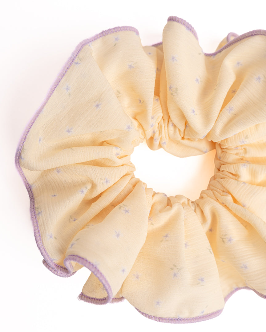 Close-up of yellow sheer floral hair scrunchie showing fabric texture and lavender trim details