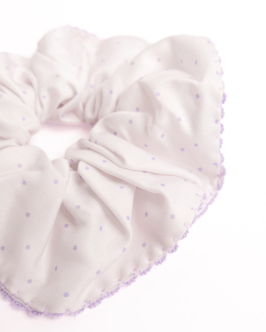 Close-up of purple polka dot silky hair scrunchie showing smooth fabric texture and scalloped crochet trim details