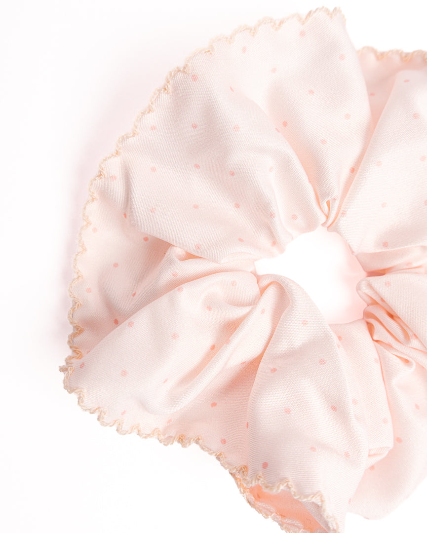 Close-up of pink polka dot silky hair scrunchie showing smooth fabric texture and scalloped crochet trim details