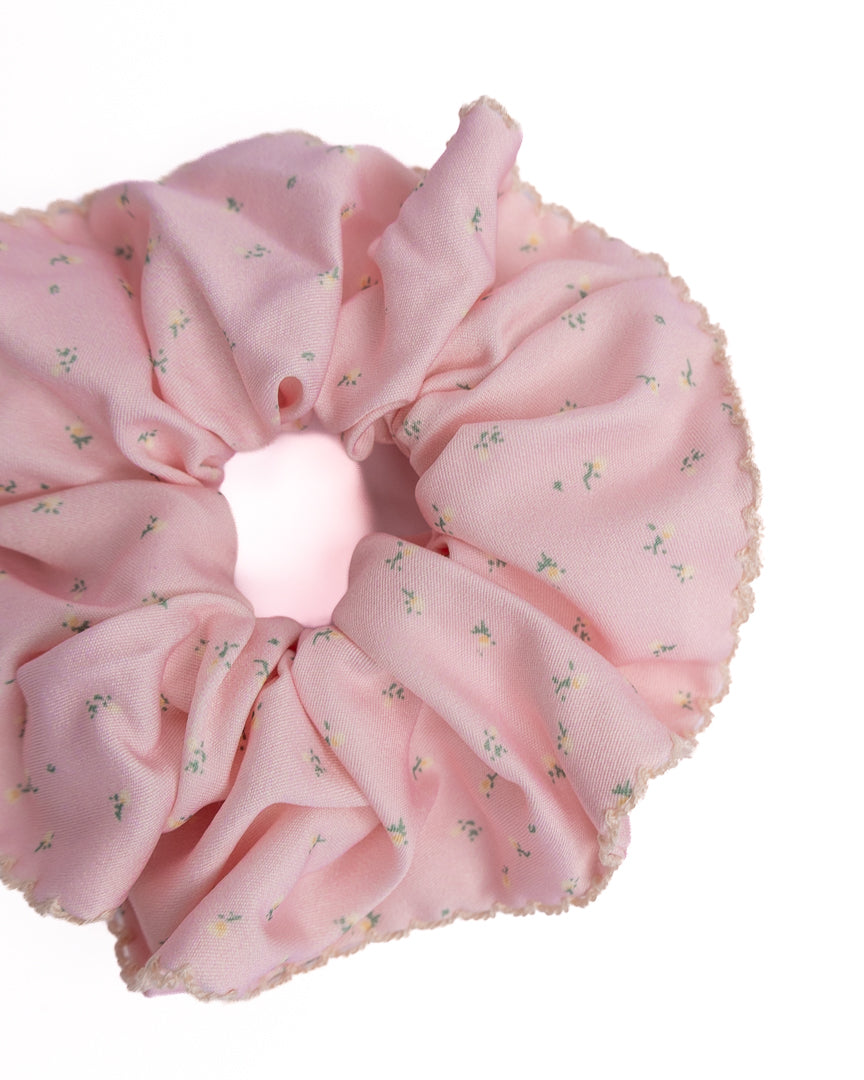 Close-up of pink ditsy floral silky hair scrunchie showing smooth fabric texture and scalloped lace trim details
