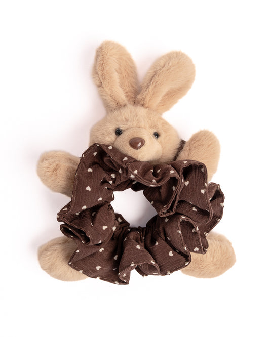 Close-up of brown plush bunny hair scrunchie showing cute rabbit face and white heart pattern fabric ruffles